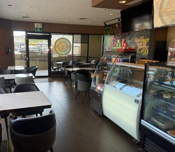 Inside the café: marble-top tables, dark chairs and the counter with its display cases